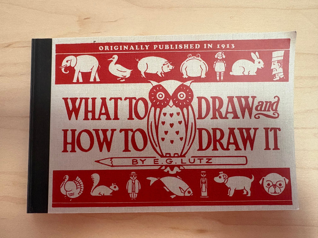 Book titled 'What to Draw and How to Draw It' by E.G. Lutz on a wooden surface