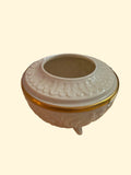 Decorative white container with gold rim on a beige surface